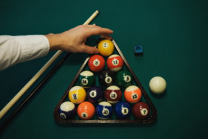 Playing billiard. Billiards balls and cue on green billiards table. Caucasian player put yellow ball inside. View from up. Billiard sport concept. Pool billiard game.