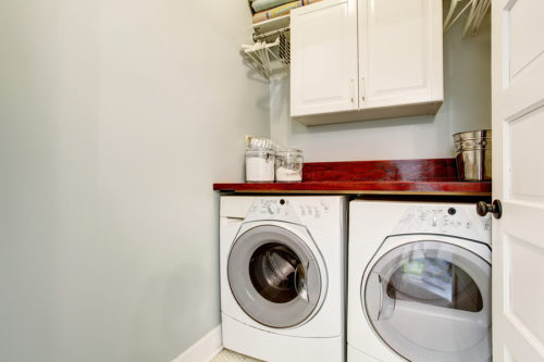 Small laundry room with tile floor door and washer dryer set.