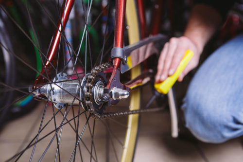 A man applies a lubricant to his bike cables before putting it into bicycle storage
