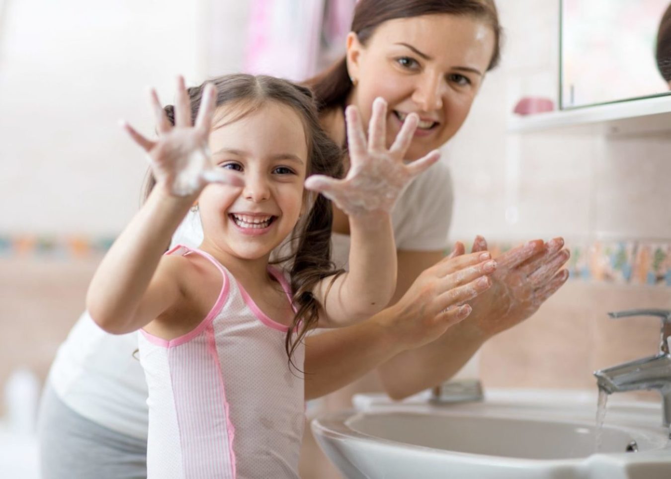 A little girl excited about washing her hands with her mother