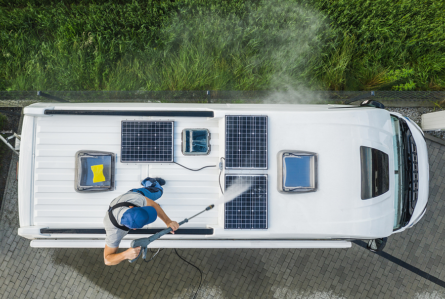 A man cleans the top of his RV camper before winter storage.